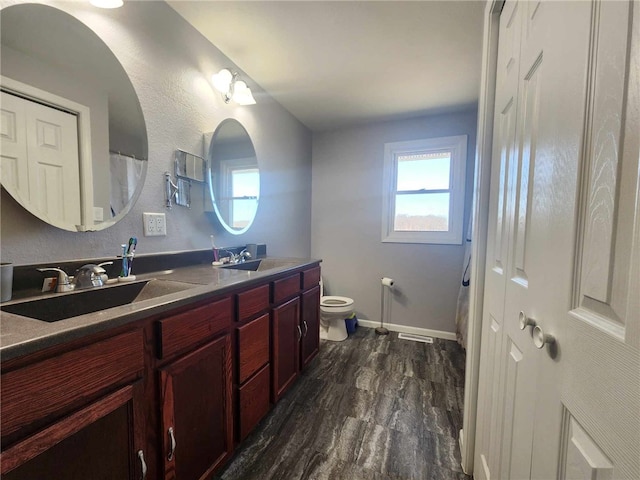 full bathroom with double vanity, wood finished floors, a sink, and toilet