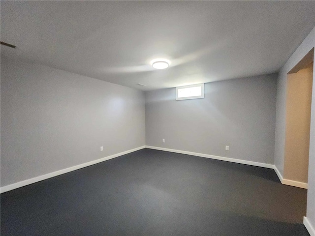 empty room with visible vents, baseboards, and dark carpet