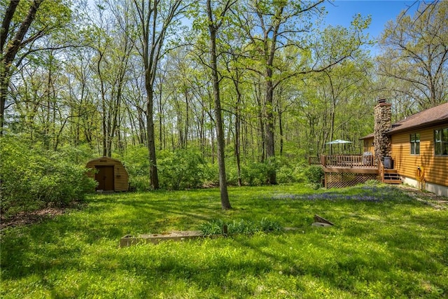 view of yard featuring an outdoor structure, a shed, and a wooden deck
