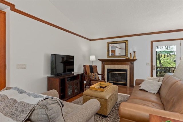 living area featuring ornamental molding, wood finished floors, vaulted ceiling, and a tile fireplace