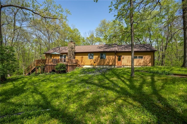 back of property with a lawn, a wooden deck, and stairs