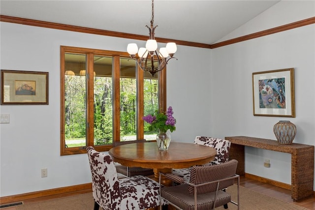 dining area with crown molding, a notable chandelier, baseboards, lofted ceiling, and visible vents