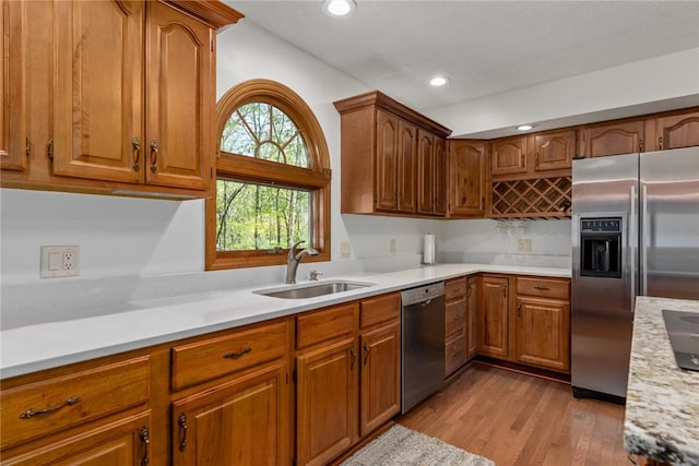 kitchen with appliances with stainless steel finishes, a sink, light wood-style floors, light countertops, and recessed lighting