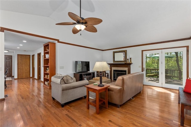 living area featuring ceiling fan, vaulted ceiling, light wood finished floors, a glass covered fireplace, and recessed lighting