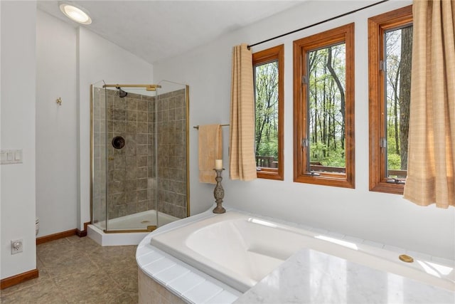 bathroom featuring baseboards, a shower stall, and a garden tub