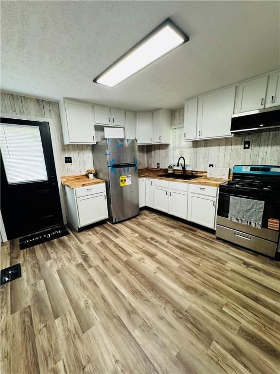 1404 N 24th St, Decatur, IL 62526 - kitchen featuring wood counters, appliances with stainless steel finishes, range hood, a sink, and white cabinetry
