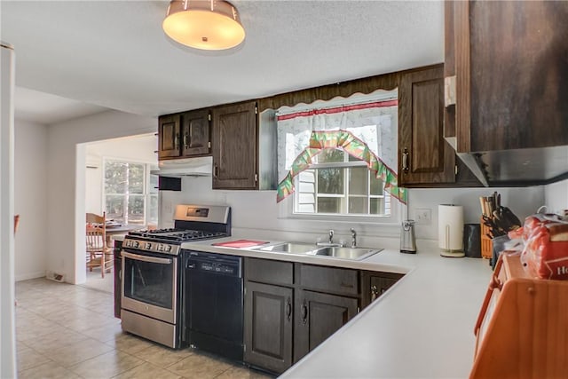 kitchen featuring stainless steel gas range oven, under cabinet range hood, a sink, black dishwasher, and light countertops