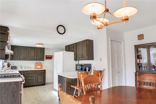 kitchen with stainless steel microwave, white refrigerator with ice dispenser, exhaust hood, light countertops, and gas range