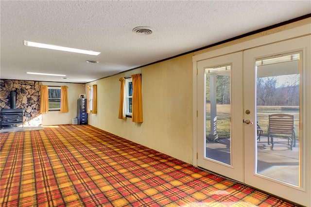 interior space featuring visible vents, french doors, a textured ceiling, and a wood stove