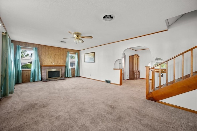 801 N Central Ave, Paris, IL 61944 - unfurnished living room featuring carpet floors, arched walkways, ceiling fan, a brick fireplace, and wood walls