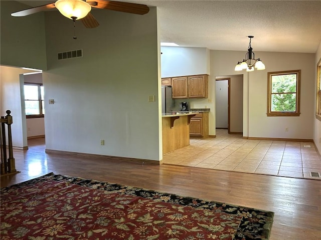 3002 N Charlotte St, Effingham, IL 62401 - kitchen featuring freestanding refrigerator, ceiling fan, light countertops, a chandelier, and a breakfast bar