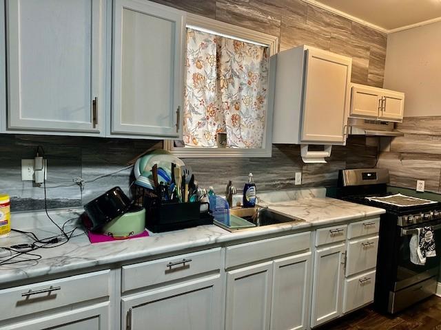 kitchen featuring white cabinetry, stainless steel range oven, light stone counters, and decorative backsplash