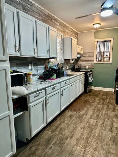 kitchen featuring electric range, ornamental molding, dark hardwood / wood-style flooring, ceiling fan, and white cabinets