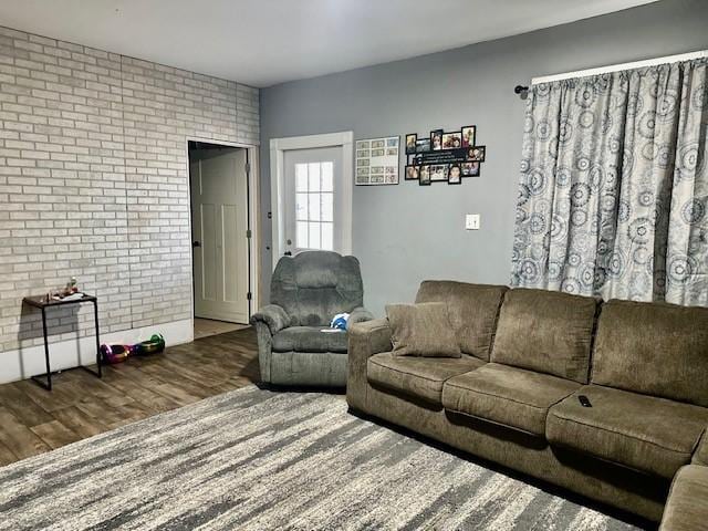 living room with brick wall and dark hardwood / wood-style floors