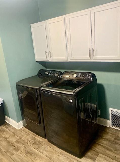 laundry area with cabinets, independent washer and dryer, and light wood-type flooring