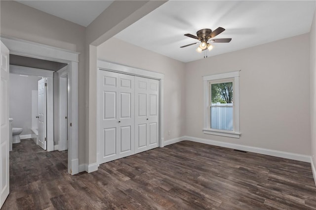 unfurnished bedroom with ceiling fan, dark wood-type flooring, connected bathroom, and a closet