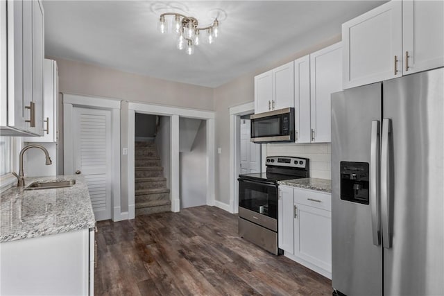 kitchen featuring stainless steel appliances, sink, light stone counters, white cabinets, and tasteful backsplash