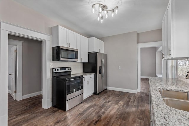 kitchen featuring stainless steel appliances, light stone countertops, sink, white cabinetry, and tasteful backsplash