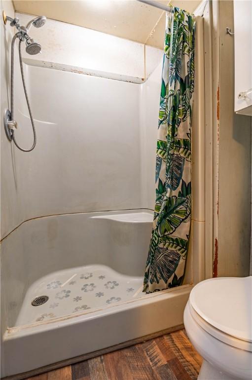 bathroom with a shower with curtain, toilet, and hardwood / wood-style flooring