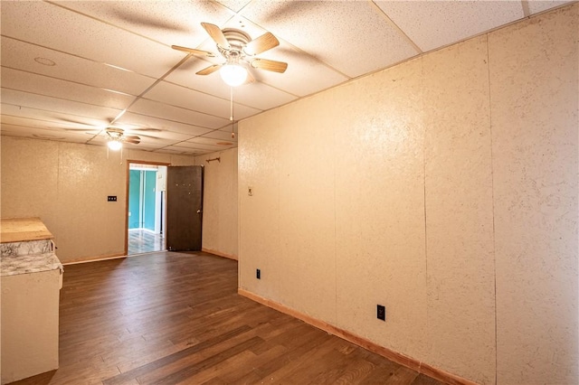 spare room featuring ceiling fan, dark hardwood / wood-style flooring, and a drop ceiling