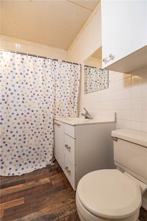 bathroom featuring vanity, toilet, wood-type flooring, and tile walls