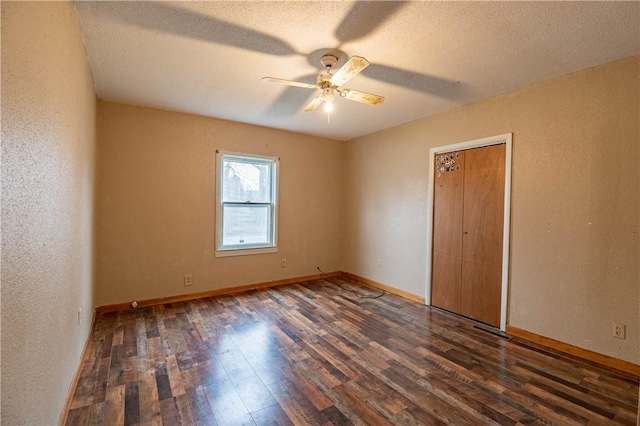 spare room with a textured ceiling, ceiling fan, and dark wood-type flooring