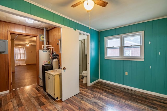 interior space featuring wooden walls, gas water heater, crown molding, and dark wood-type flooring