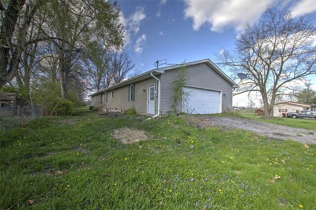 view of side of home featuring an attached garage, aphalt driveway, and a lawn