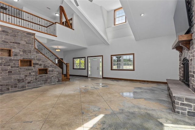 2098 2070th Ave, Saint Elmo, IL 62458 - unfurnished living room with a high ceiling, healthy amount of natural light, a stone fireplace, and stairway