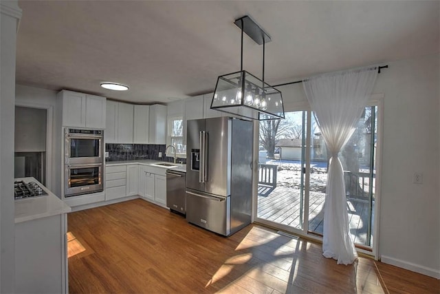 kitchen with white cabinetry, sink, pendant lighting, and appliances with stainless steel finishes