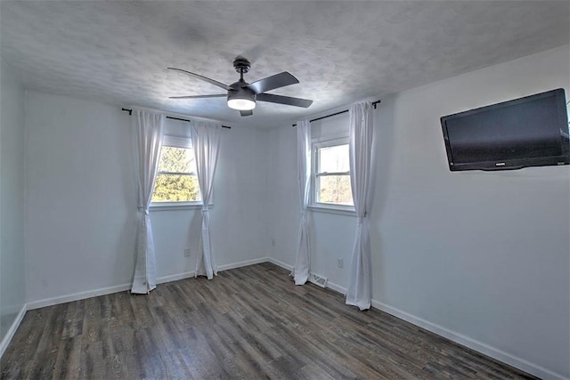 empty room featuring dark hardwood / wood-style flooring, ceiling fan, and a textured ceiling