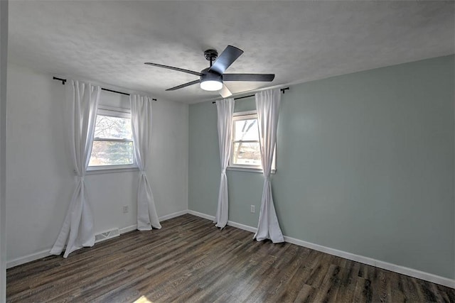 empty room with a textured ceiling, plenty of natural light, dark hardwood / wood-style floors, and ceiling fan