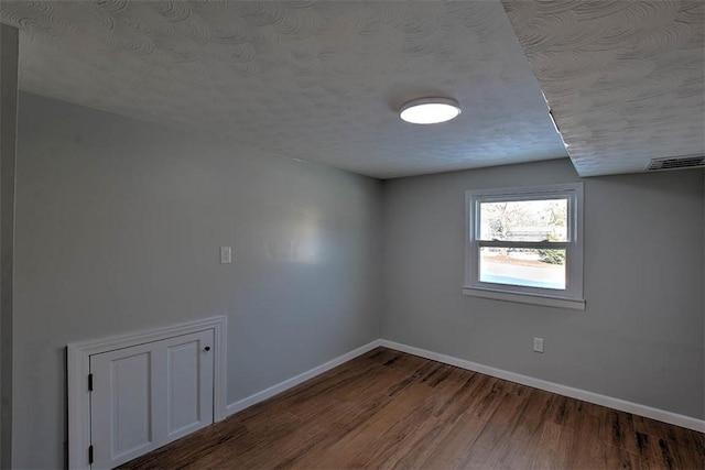 empty room with hardwood / wood-style floors and a textured ceiling