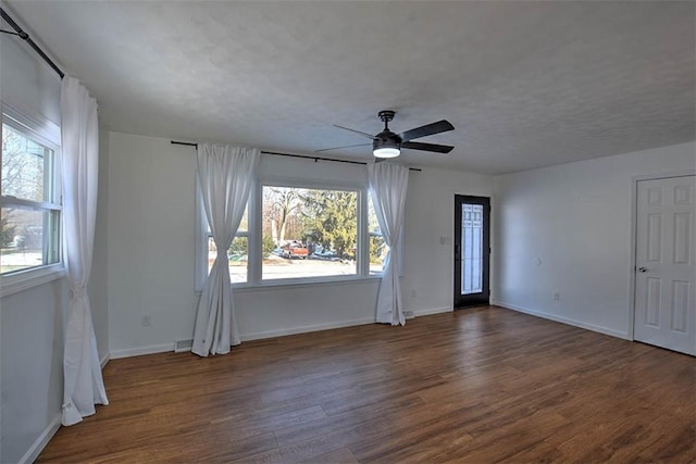 empty room with dark wood-type flooring, ceiling fan, plenty of natural light, and a textured ceiling