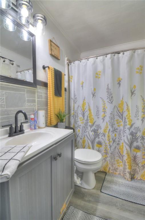 805 N 33rd St, Decatur, IL 62521 - bathroom with toilet, wood finished floors, crown molding, decorative backsplash, and vanity