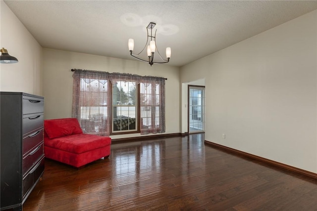 sitting room featuring dark hardwood / wood-style flooring, an inviting chandelier, and a textured ceiling