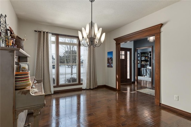 unfurnished dining area with a textured ceiling, dark hardwood / wood-style floors, and a notable chandelier