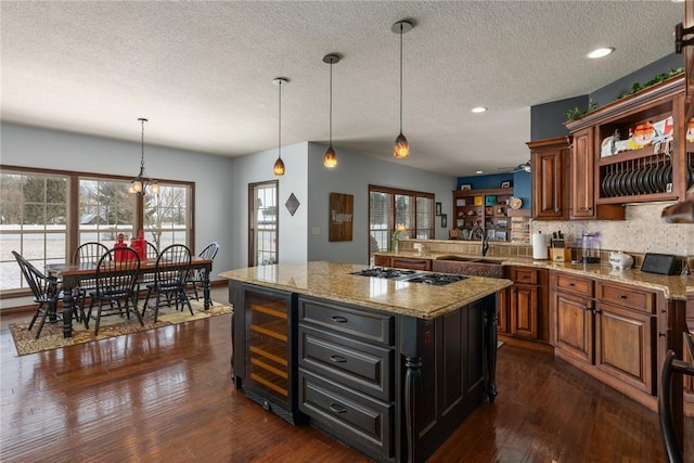 kitchen with gas stovetop, pendant lighting, light stone countertops, and beverage cooler