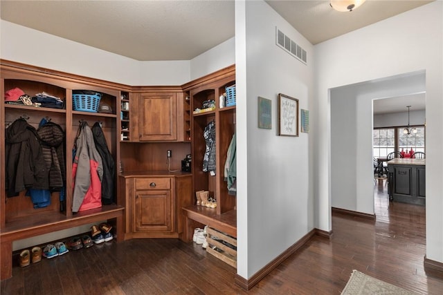 mudroom featuring dark wood-type flooring and an inviting chandelier