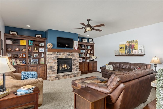 living room featuring ceiling fan, a stone fireplace, and carpet flooring