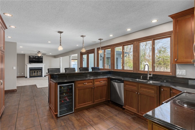 kitchen with sink, beverage cooler, a premium fireplace, stainless steel dishwasher, and pendant lighting