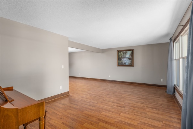 empty room with a textured ceiling and light hardwood / wood-style flooring