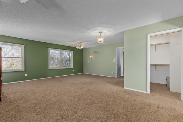 interior space with multiple windows, ceiling fan, carpet floors, and a textured ceiling