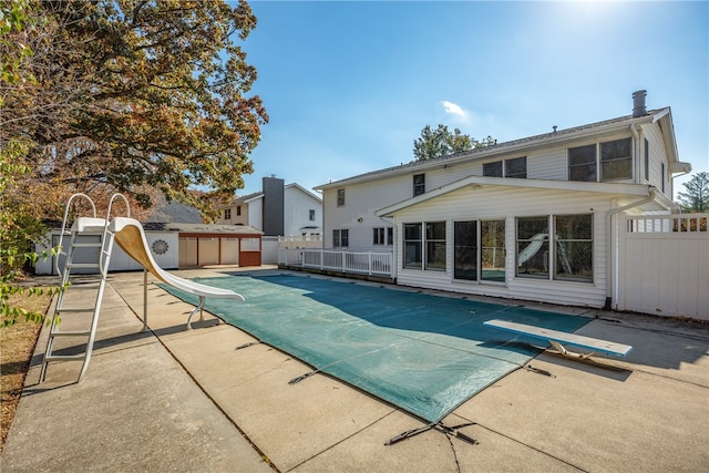 view of swimming pool with a diving board, a patio area, and a water slide