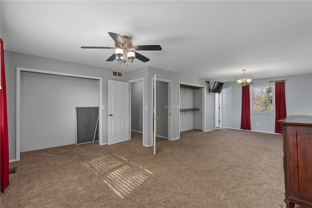 interior space with carpet flooring, a textured ceiling, ceiling fan with notable chandelier, and multiple closets