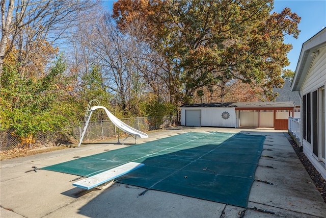 view of pool with a diving board, a water slide, and a patio