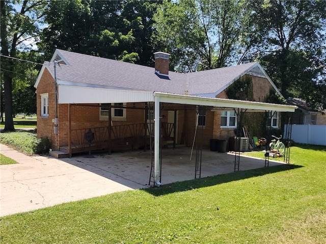 410 E Ninth St, Pana, IL 62557 - back of house with brick siding, a chimney, an attached carport, and a shingled roof