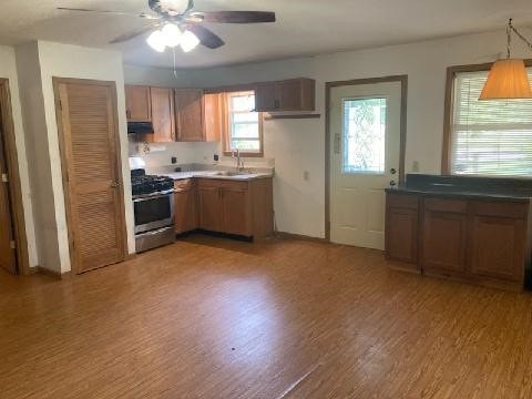 13859 Lake Jasper S Ave, Newton, IL 62448 - kitchen with stainless steel range with gas stovetop, wood finished floors, ceiling fan, brown cabinetry, and decorative light fixtures