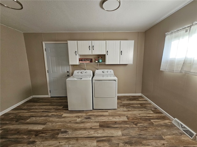 clothes washing area featuring dark wood finished floors, visible vents, cabinet space, and separate washer and dryer