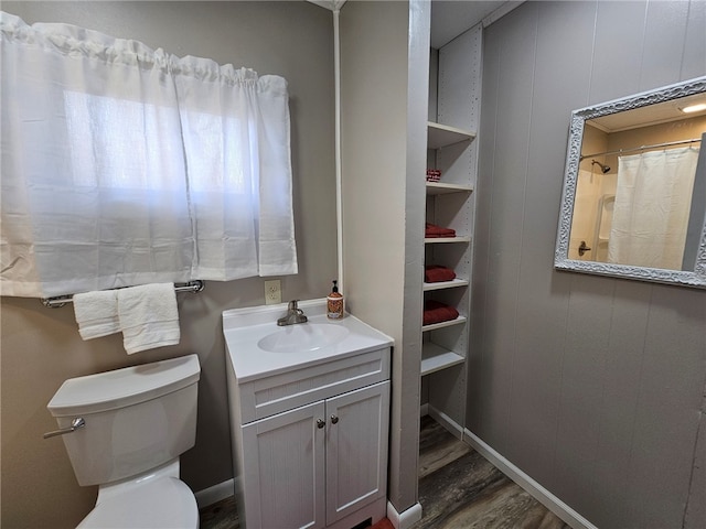 bathroom featuring toilet, wood finished floors, a shower with shower curtain, baseboards, and vanity